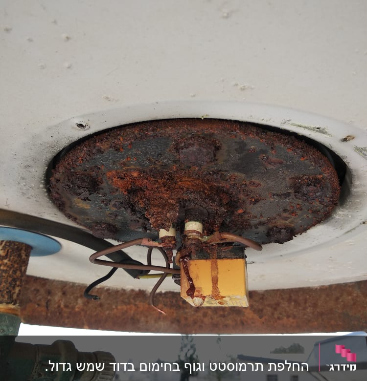 חלק תחתון של דוד שמש עם חלודה וחוטים חשמליים